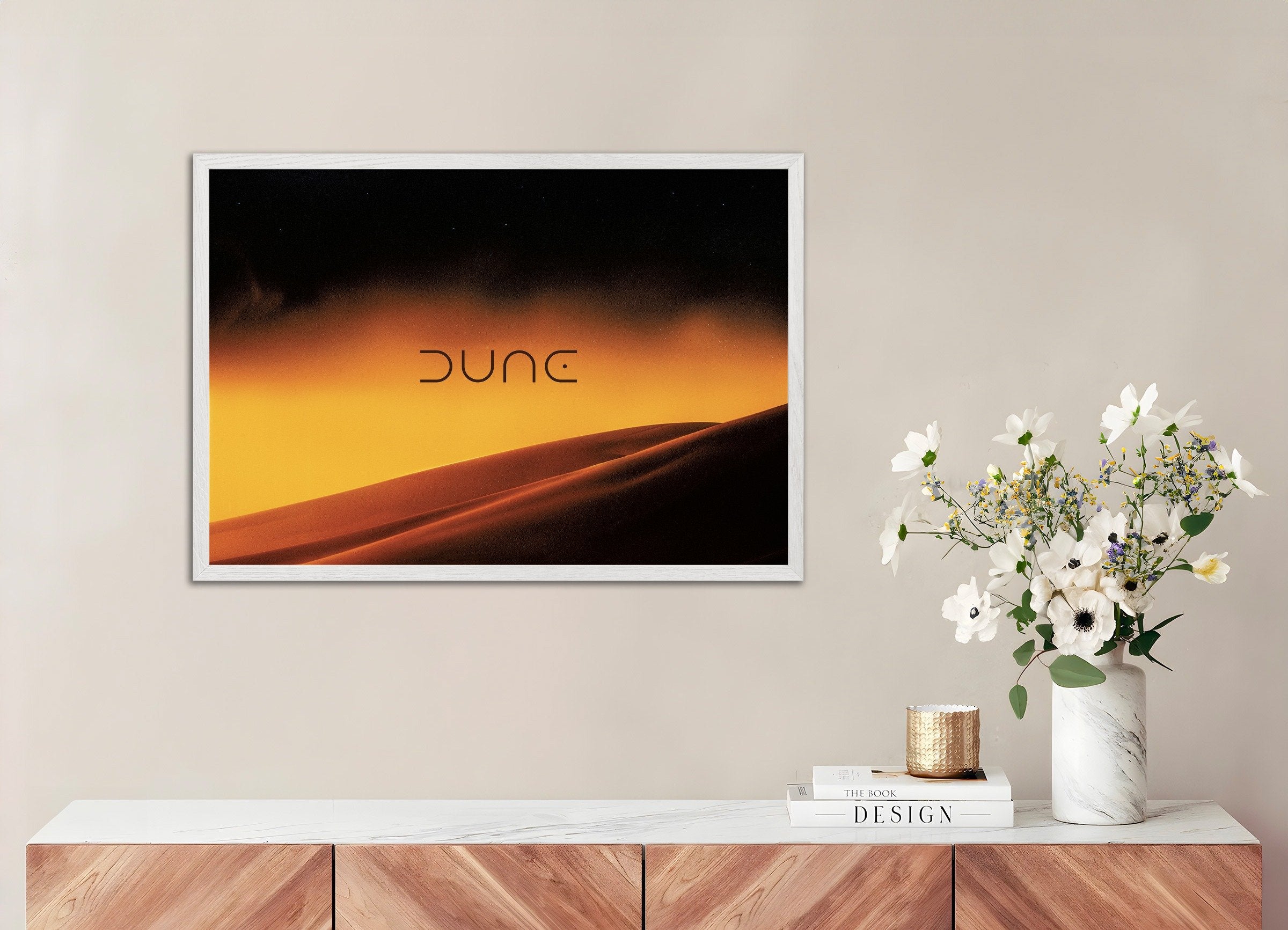 Framed artwork with 'Dune' on a wall above a wooden console table with decor items.