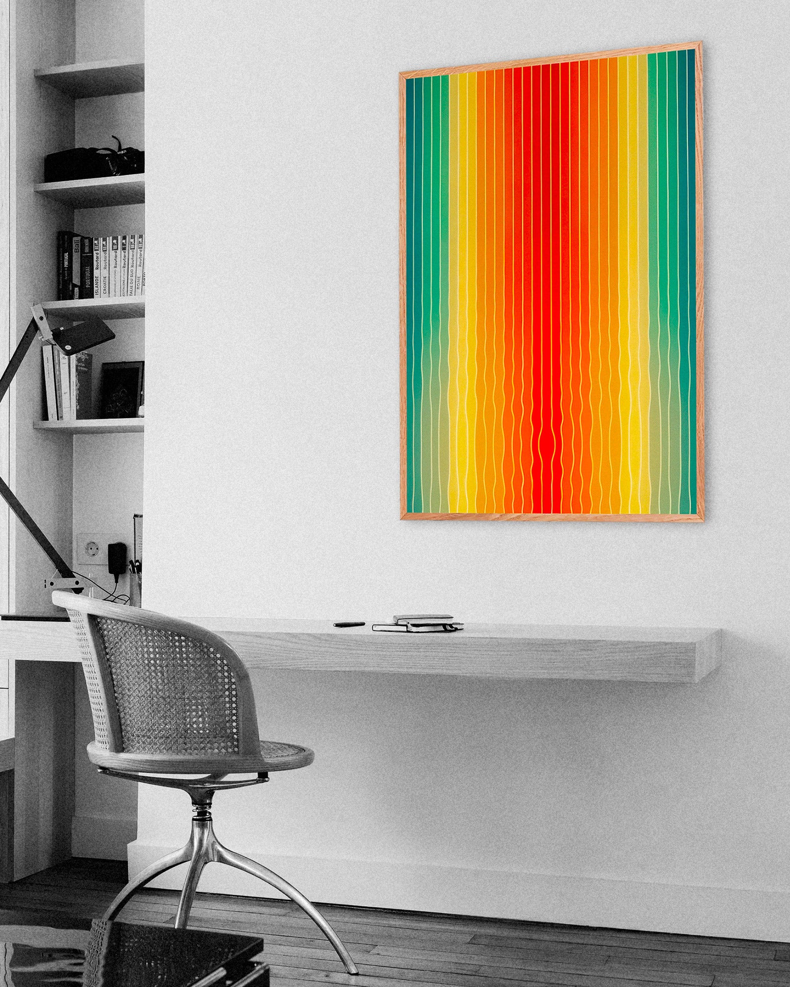 Colorful abstract painting on a white wall above a desk with a chair.